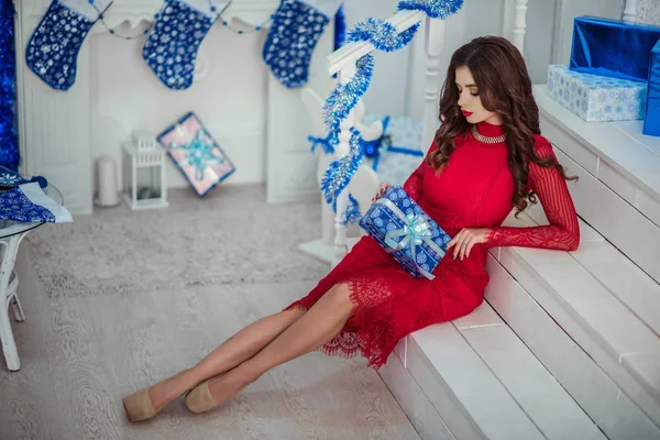 Dívka v červených šatech rozbalí dárky — Stock fotografie