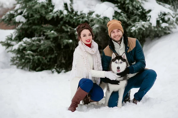 Un uomo e una ragazza camminano nella foresta invernale con un cane — Foto Stock