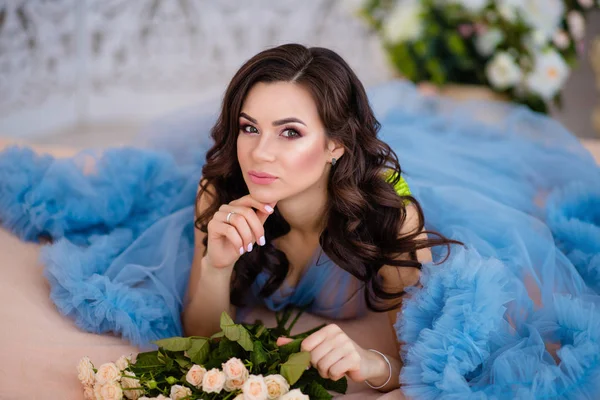 Hermosa chica con el pelo oscuro con flores en las manos en un blu — Foto de Stock