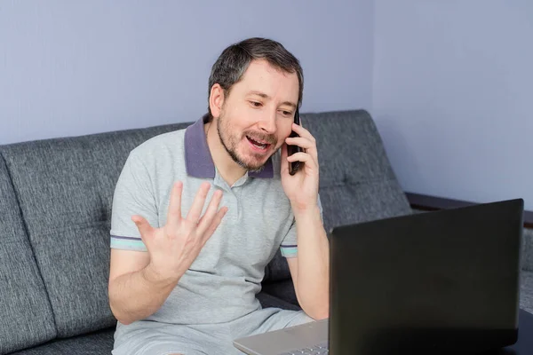 Muž Pracuje Doma Laptopem Mluví Telefonu — Stock fotografie