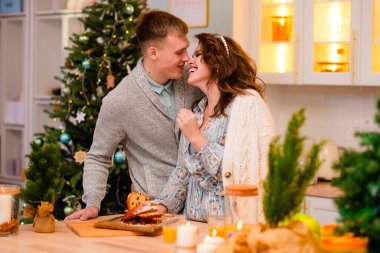 Güzel kadın ve erkek sarılıyor, noel pastasını kesiyor ve arka planda gülümsüyor.