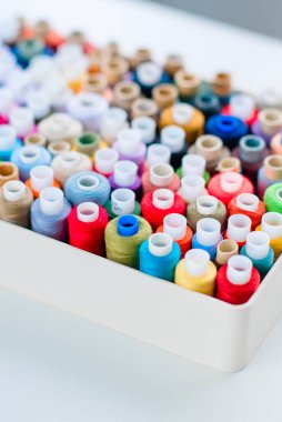 Dikiş için aksesuarlar. Beyaz arkaplanda beyaz bir tabutta renkli iplik makaraları