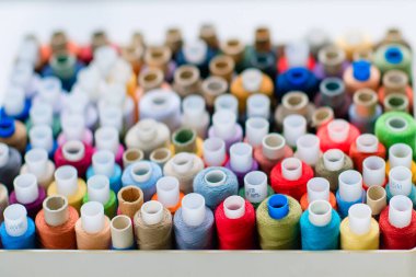 Dikiş için aksesuarlar. Beyaz arkaplanda beyaz bir tabutta renkli iplik makaraları