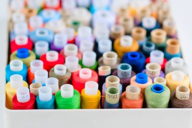 Dikiş için aksesuarlar. Beyaz arkaplanda beyaz bir tabutta renkli iplik makaraları