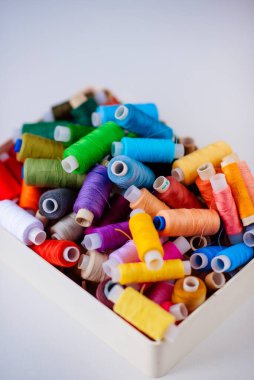 Dikiş için aksesuarlar. Beyaz arkaplanda beyaz bir tabutta renkli iplik makaraları