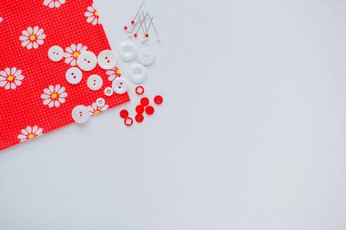 El dikimi için aksesuarlar. İğneler, düğmeler, kurdeleler. Beyaz arkaplanda makas, renkli kumaş.