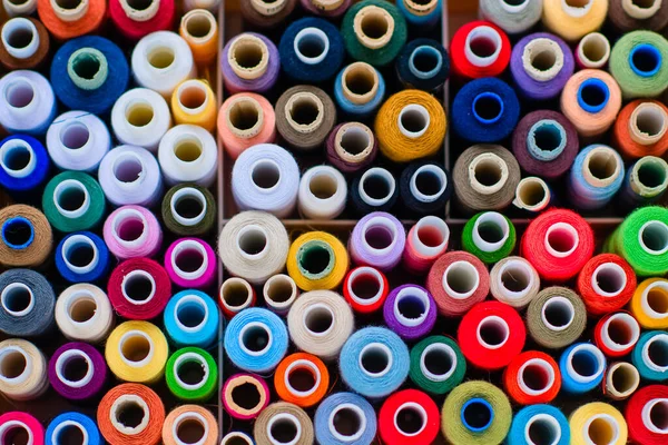 Dikiş için aksesuarlar. Beyaz arkaplanda beyaz bir tabutta renkli iplik makaraları