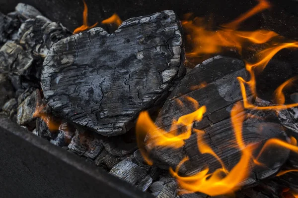Carvões quentes e madeiras em chamas na forma de coração humano. Carvão brilhante e flamejante, fogo vermelho brilhante e cinzas. .Close-up, vista superior . — Fotografia de Stock