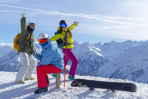 Τρεις χαρούμενοι φίλοι snowboarders και σκιέρ διασκεδάζουν στην πλαγιά του σκι με σκι και snowboards στην ηλιόλουστη μέρα. — Φωτογραφία Αρχείου