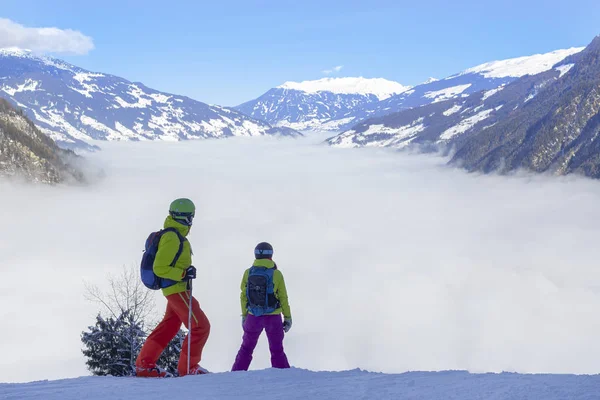 Fiume di nebbia bianca in montagna e due persone di fronte, snowboarder e sciatori si preparano per la discesa. — Foto Stock