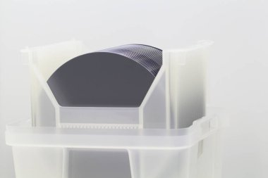 Silicon Wafers in white plastic holder box on a table- A wafer is a thin slice of semiconductor material, such as a crystalline silicon, used in electronics for the fabrication of integrated circuits. clipart