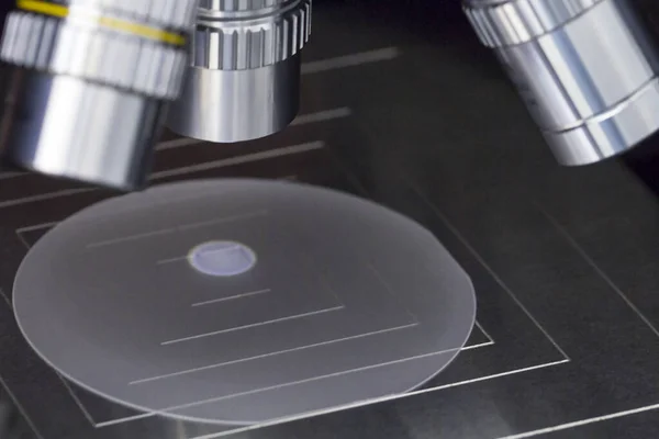 Sluiten van het onderzoeken van een monster van saffier wafer onder de microscoop in laboratorium.Een halfgeleider op een silicium wafer. Selectieve focus. — Stockfoto