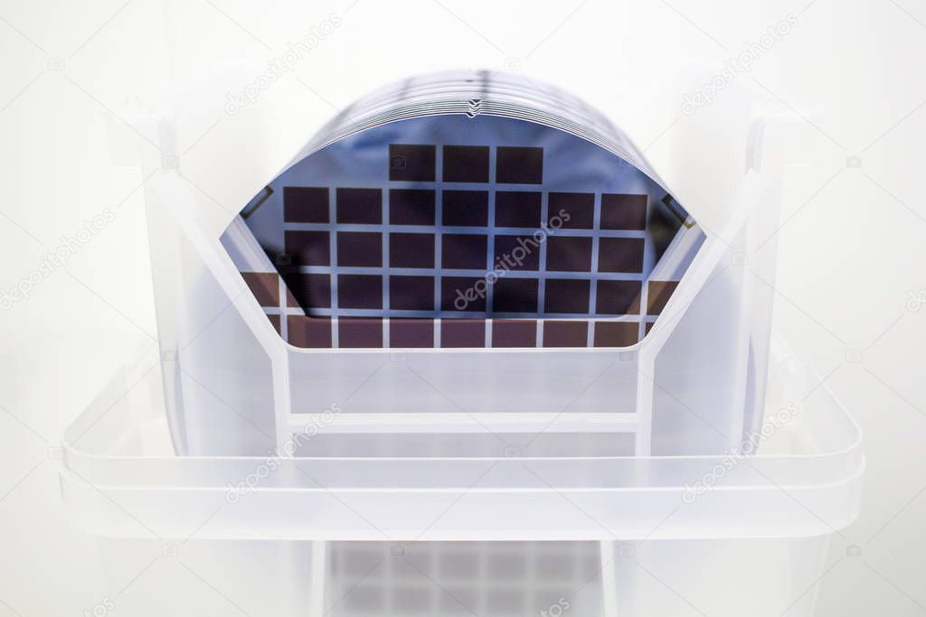 Silicon Wafers in white plastic holder box on a table- A wafer is a thin slice of semiconductor material, such as a crystalline silicon, used in electronics for the fabrication of integrated circuits.