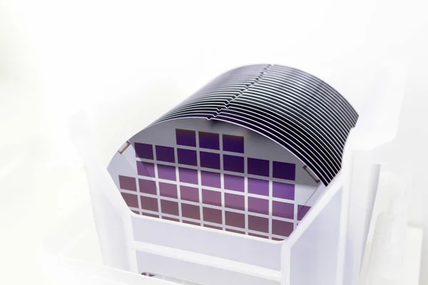 Silicon Wafers in white plastic holder box on a table- A wafer is a thin slice of semiconductor material, such as a crystalline silicon, used in electronics for the fabrication of integrated circuits.