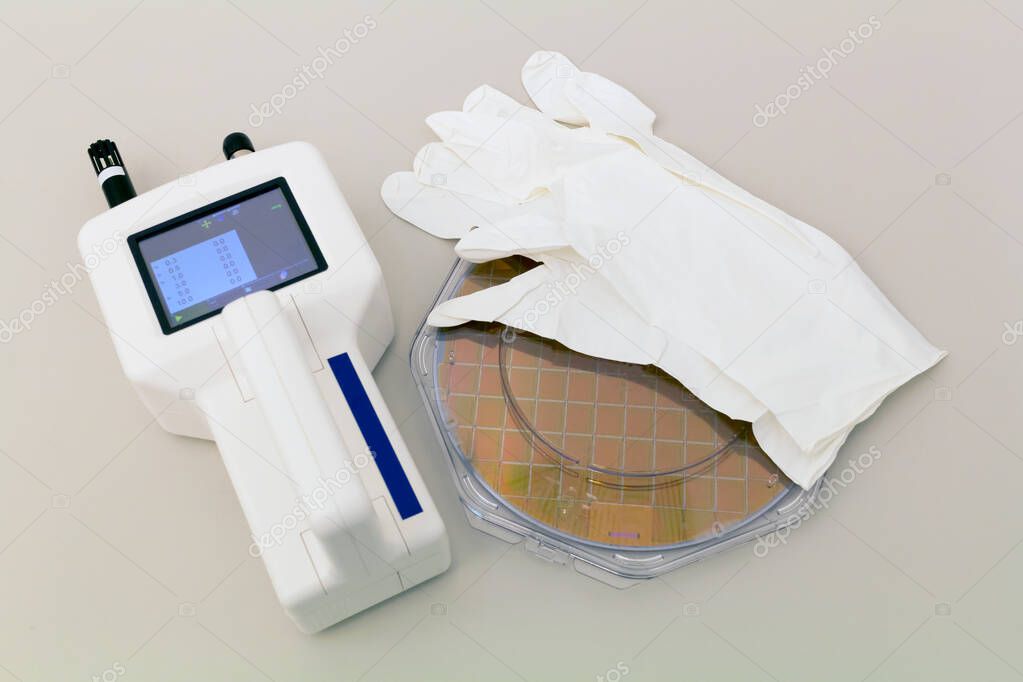 Silicon Wafer in plastic holder box on a table with particle counter near.