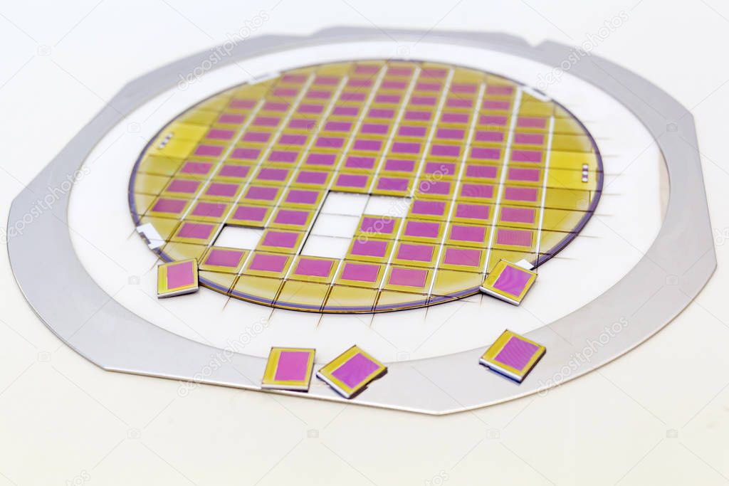 Silicon wafer with microchips fixed in a holder with a steel frame after the dicing process and separate microchips.