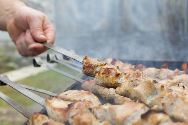 Adam yemek pişiriyor, sadece elleri var. Yemek için et ya da biftek kesiyor. Izgarada nefis ızgara et. Barbekü haftasonu.