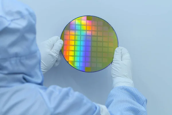 Ingenieur in duidelijke kamer in witte handschoenen en pak met een siliconen wafel op een witte achtergrond. — Stockfoto