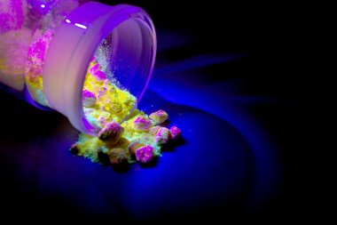 Üretim için kırmızı, sarı ve yeşil renkli floresan organik maddeler UV ışığıyla cam şişenin içinde. Organik ışık diyot yayıyor..