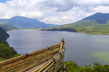 Ön planda bir tekne ve doğada göl ve dağların manzarası..