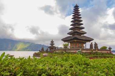 Endonezya, Bali 'deki sönmüş volkan kraterinde bulutlu bir günde Beratan Gölü üzerindeki güzel Balili Ulun Danau tapınağı.