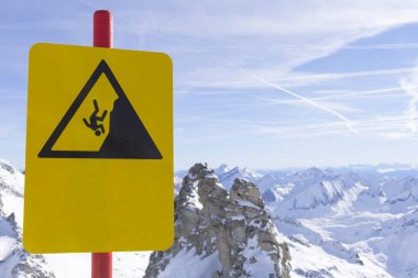 Dağlardaki kayak merkezindeki uyarı levhası. Dikkatlice kayalıklardan aşağı inin. Avrupa 'nın tepesindeki Tirol' de Alp Dağları manzarası