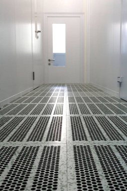 Inside the cleanroom of semiconductor manufacturing.Hallway with raised floor and door in cleanroom for pharmaceutical or electronic industry. clipart