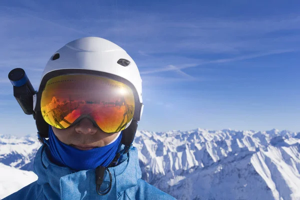 穿着白色头盔的滑雪者戴着橙色滑雪眼镜，在阿尔卑斯山顶上拍照。在高山的背景上。近景. — 图库照片