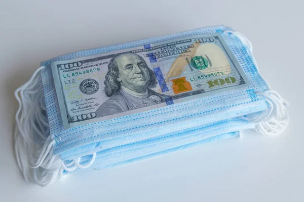 Bir paket tıbbi maske ve 100 dolarlık banknotlar daha yüksek fiyatların sembolü ve solunum yollarının virüslerden korunmasında bir eksiklik. Koruyucu maskelerin fiyatını arttırdı.