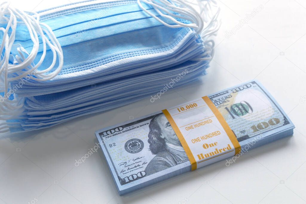 Blue medical masks, and american money.High price of masks and demand during quarantine in United States, Europe and global pandemic. Pile of anti virus surgical face masks and money. Concept.