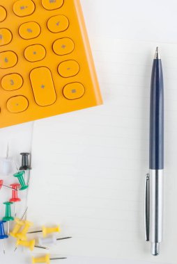 kalem, hesap makinesi ve raptiye beyaz kağıt üzerinde 