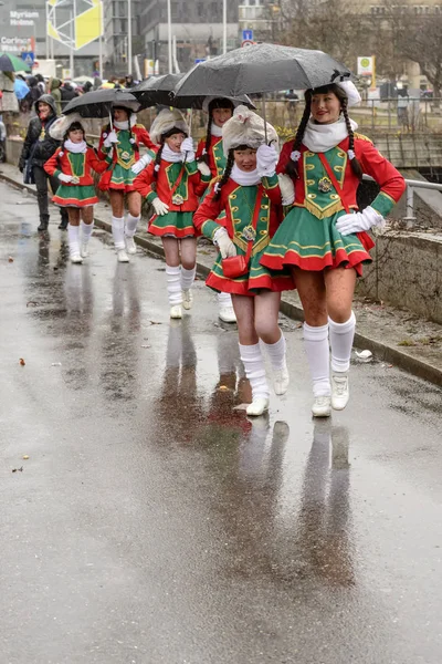 Line of majorettes march under black umbrella at Carnival parade — Stock Photo, Image