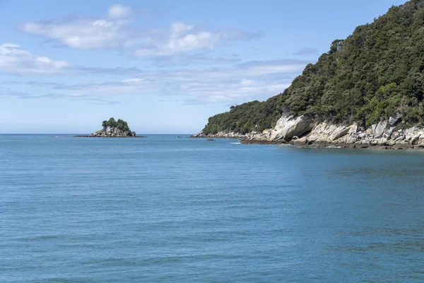 Yeşil küçük Dolly Varden adası ve Anchorage körfezindeki yağmur ormanları yemyeşil bitki örtüsüyle kaplı manzara, Kaiteriteri, Abel Tasman parkı, Güney Adası, Yeni Zelanda yakınlarındaki parlak bahar ışığında çekildi.