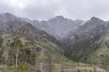 Düşük bulutlu ve bahar karlı bir manzara. Olağanüstü sıradağlarda. Drift Körfezi, Otago, Güney Adası, Yeni Zelanda 'dan parlak bahar ışığı altında çekilmiş.