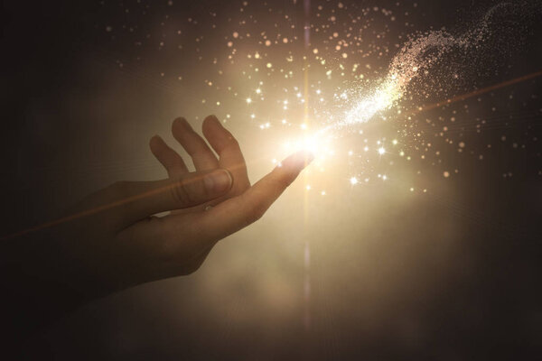 A hand giving the flow of energy. Magic, fantasy. Glowing particles