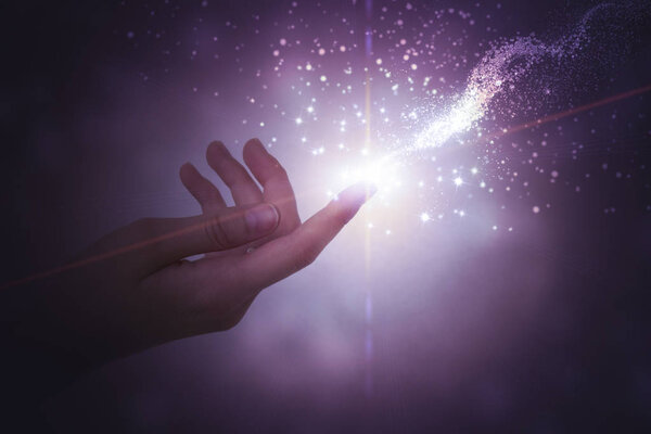 A hand giving the flow of energy. Magic, fantasy. Glowing particles