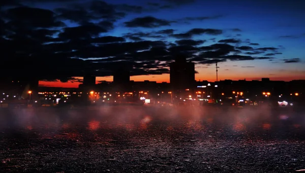 Gece sokağının dramatik arka planı, asfalt üzerindeki spot ışığı, duman. Gece şehrinin ışıkları