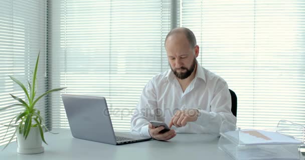 Businessman With Laptop Uses The Smartphone In Office in 4K — Stock Video