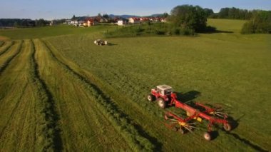 Anteni traktörün saman sahada yeşil hat güneşli bir günde 4 k dağlarında toplar