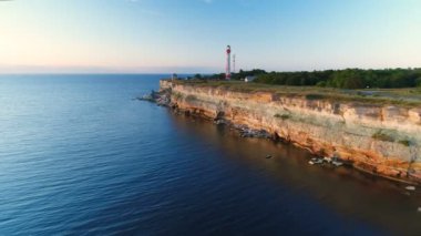 Uçuruma boyunca dron hava uçan sahilde günbatımı, yaz aylarında deniz feneri bakan