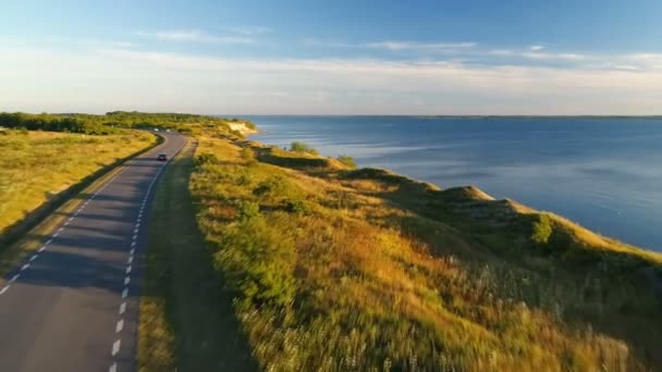 夕暮れの夏の海の近くの崖沿いの道を運転の空中写真 — ストック動画