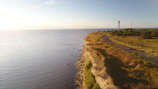 在夏季日落时 沿海崖驾驶黑色汽车的鸟瞰图 在背景老灯塔 — 图库视频影像
