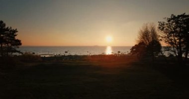 Bir yolcu gemisi günbatımında bakan ağaçlar denizde kıyıdan hava uçuş