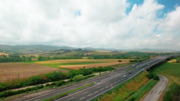 在黄色和绿色的草地之间的公路上驾驶车辆的鸟瞰图 意大利托斯卡纳夏季晴天的田野和乡村居住区鸟瞰图 — 图库视频影像