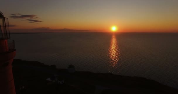 灯塔在日落背景在海在夏天 空中飞行的无人机通过灯塔在日落 灯塔给海洋中的船只发出光信号 — 图库视频影像