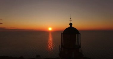 Eski deniz feneri yaz aylarında deniz günbatımı bir arka plan üzerinde çalışıyor. Gün batımında hava uçan fener geçmiş dronun. Deniz feneri deniz gemilere ışık sinyalleri verir