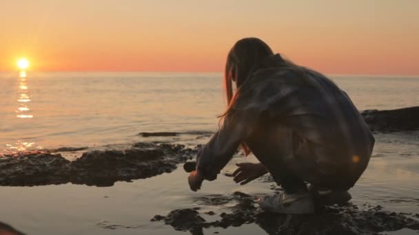 一个小女孩用海水在海边洗手和洗脸 日落在海 慢动作 — 图库视频影像