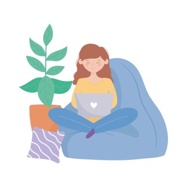 Evde kalıp dizüstü bilgisayar kullanan bir kadın kanepe ve yastık süslemesinde oturuyor.