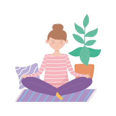 Evde kalıp yoga yapan genç bir kadın poz veriyor.