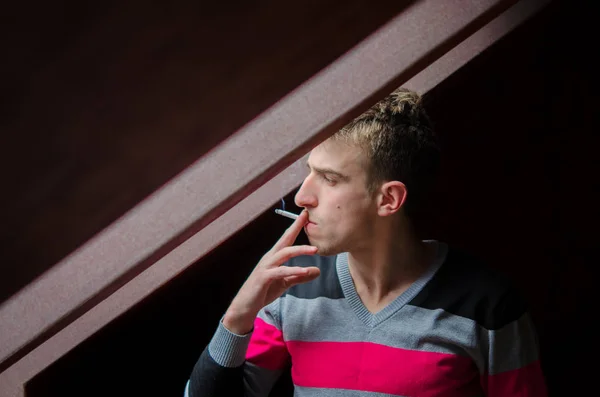 Jeune homme fumant sa cigarette du matin par la fenêtre tout mince — Photo